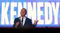 Robert F. Kennedy Jr. puhuu mikkiin. Taustalla on teksti "KENNEDY".