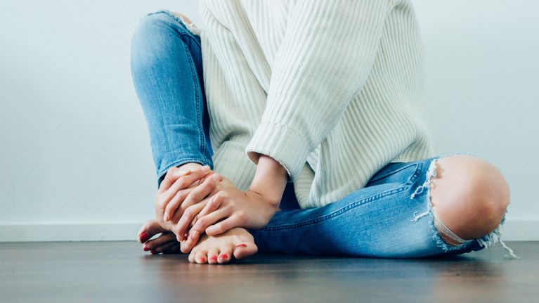 henkilö istuu lattialla, jalat ja kädet vain näkyy