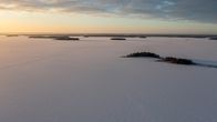 Talvinen Lappajärvi ilmasta kuvattuna. Pieniä saaria ja aurinko laskemassa.