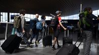 Matkustajat vetävä matkalaukkuja lentokentällä.