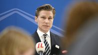 Antti Häkkänen puku päällä median mikrofonien edessä.
