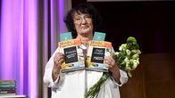 Monika Fagerholm pitelee käsissään kahta kirjaa ja kukkia.