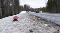 Kynttilöitä ja vaaleanpunainen kukkakimppu on tuotu maantien laidalle lumeen.