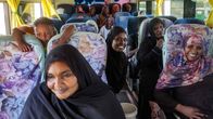 Sudanilaiset matkaajat reagoivat kuvaajaan bussissa, jossa on kukalliset penkinsuojat ja keltaiset verhot.