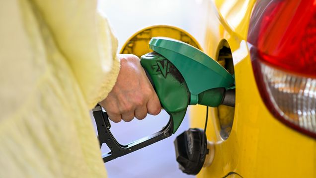 Photo shows a person's hand filling a petrol tank.