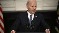 En äldre man, Joe Biden, står vid en talarstol med blicken vänd mot höger.