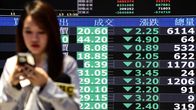 Nainen kävelee osakkeiden keskikursseja näyttävien näyttöjen ohi Taiwanin pörssissä.
