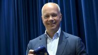 Christoph Vitzthum katsoo kameraan ja pitelee suklaalevyä kädessä.