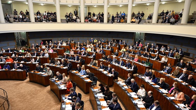 Kansanedustajia ja yleisöä eduskunnan istuntosalissa.
