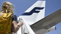 Passenger with a yellow backpack seen from behind walking up a staircase leading to the rear of a Finnair jet.