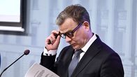 Petteri Orpo katsoo papereita tiedotustilaisuudesas.