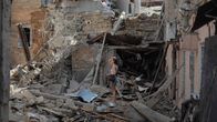 Woman standing in the ruins of a destroyed building.