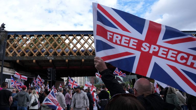Demonstranter. I förgrunden en brittisk flagga med texten "free speech".