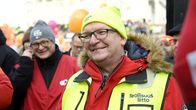 Riku Aalto klädd i vinterkläder med en reflexväst på sig. Han ler och tittar åt sidan. I bakgrunden fler människor.