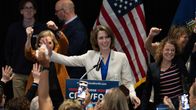 Crawford, i vit kavaj, står vid ett podium med texten "Judge Crawford for WI". Personer brevid henne höjer sina armar till stöd för henne. 