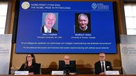 Nobelvoittajat näytöllä ja edessä Nobel-virkailijoita.