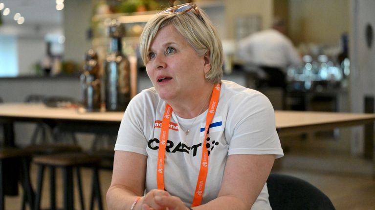 Leena Huovinen mediatilaisuudessa aurinkolasit otsallaan ja oranssi kaulanauha kaulassaan.