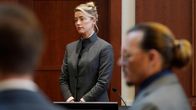Amber Heard seisoo oikeudessa. Etualalla Johnny Depp epäterävänä.