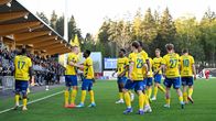 Jalkapalloilijat juhlivat maaliaan kotiyleisön edessä aurinkoisella stadionilla.