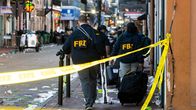 FBI:n rikostutkijat suorittavat tutkintaa paikan eristämisen jälkeen. Kadulla näkyy roskia ja ohikulkijoiden tavaroita.