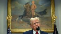 Trump talar i en mikrofon. I bakgrunden en tavla som föreställer Theodore Roosevelt ridande på en häst. 