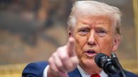 En närbild på Trump där han har en mikrofon framför hakan och pekar rakt fram mot kameran med sitt pekfinger. 