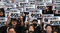 Ihmisillä koreankielisiä plakaatteja mielenosoituksessa