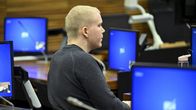 Aleksanteri Kivimäki istuu oikeussalissa ympärillään sinisiä monitoreja.
