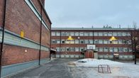 Punatiilisen koulurakennuksen piha talvisena päivänä.