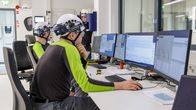 Puukuitutuotteita valmistavan koetehtaan valvomo. Kaksi miestä tarkkailee tehtaan toimintaa ja prosesseja tietokonenäytöiltä.