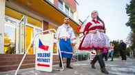 Kaksi kansallispukuun pukeutunutta henkilöä poistuu äänestyspaikalta.