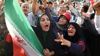 Iranska kvinnor med arga, upprörda miner och klädda i slöja viftar med en iransk flagga under en demonstration.
