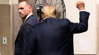 Donald Trump selin poistumassa oikeussalista oikea käsi nyrkissä kohotettuna.