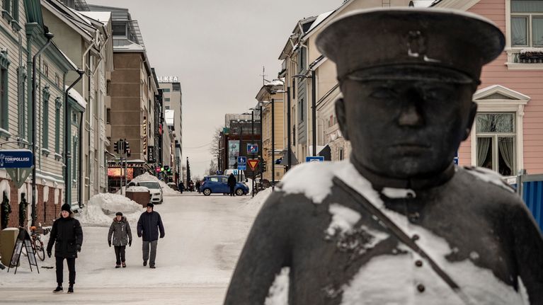 Ihmisiä kävelee Oulun Toripoliisin patsaan takana