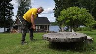 Mies avaamassa rengaskaivon kantta rautakangella.