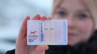 Nuoren naisen kädessä oleva ajokortti, johon on merkitty "erityisehto numero 78". Talvinen tausta.