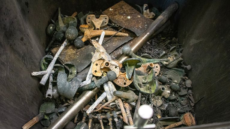 Jäteastia, jossa on suuri määrä tuhkausprosessissa eroteltuja metalleja tekonivelistä arkun osiin.