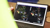 Pöydällä on tietokone, jonka näytöllä näkyy tekoälyn tuottama värillinen kaavio sähköverkon kokonaisluotettavuudesta.