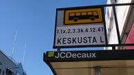 Lähikuvassa bussipysäkin kyltti ja linjanumerot