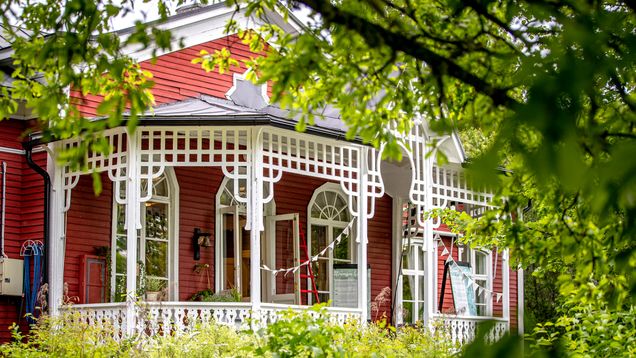 En röd villa, i förgrunden gröna löv.