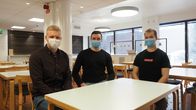 Kolme opiskelijaa istuskelee yliopiston aulassa.