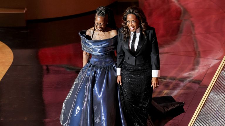 Whoopi Goldberg ja Oprah Winfrey kävelevät vierekkäin punaisella matolla.