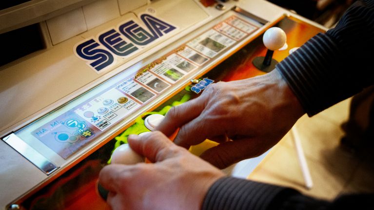 Lähikuva Segan pelikoneesta ja pelaavista käsistä.