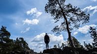 Nainen ylhäällä kalliolla katselee kohti horisonttia.