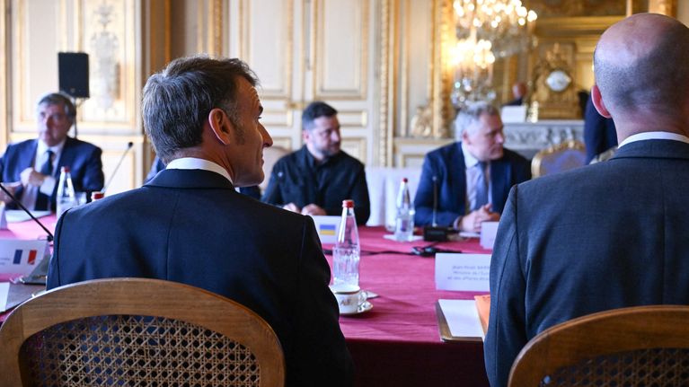Emmanuel Macron ja Volodymyr Zelenskyi istuvat vastakkain pöydän ääressä muiden kokousvieraiden kanssa.