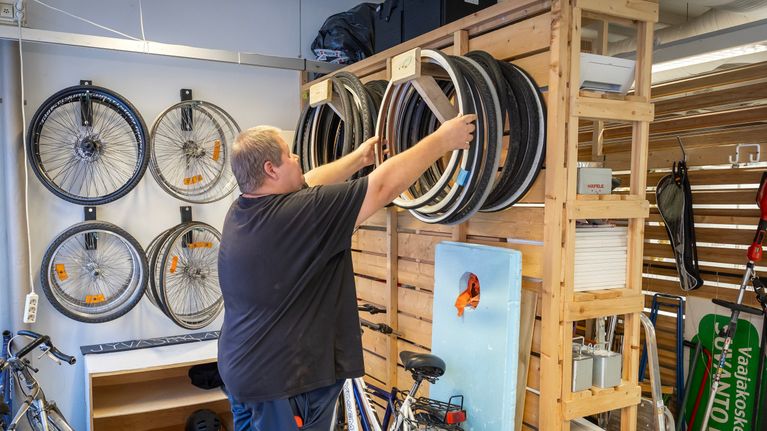 Mies nostaa polkupyörän rengasta seinälle.