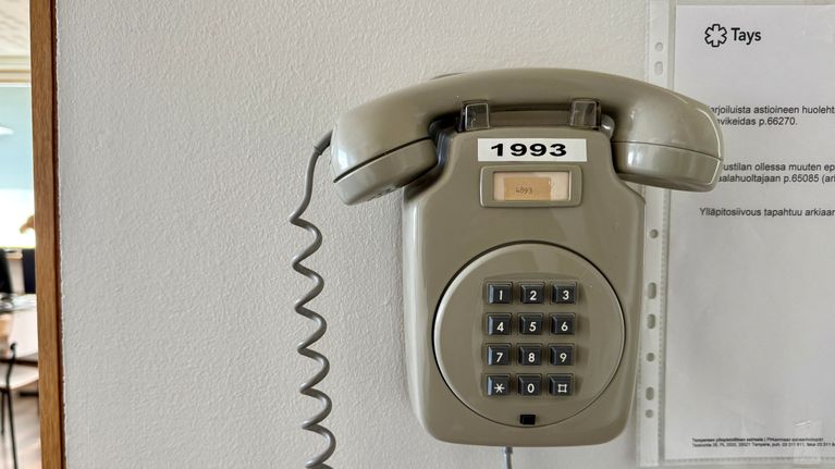 Photo shows a landline phone on a wall.