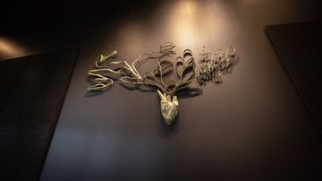 En skulptur i metall monterad på en mörk vägg.