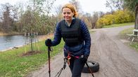 Henkilö kävelee kävelysauvojen kanssa hiekkatiellä ja vetää autonrengasta perässään.