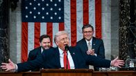 Donald Trump elehtii käsillään puhujankorokkeella. Taustalla J.D. Vance ja Mike Johnson nauravat. 